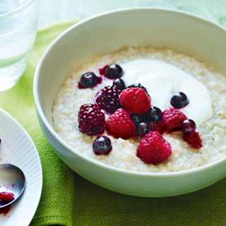 Porridge and yoghurt served in a bowl, topped with a selection of summer fruits.